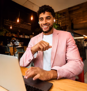 Professionnel réunionnais souriant dans un café travaillant sur son pc portable bénéficiant de l'option Cyberprotection d'Orange